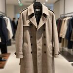 리버서블 디자인의 베이지와 브라운 체크 트렌치 코트가 매장에 걸려 있는 모습